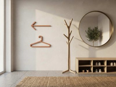 Wandmontiertes Piktogramm-Set bestehend aus einem Kleiderbügel-Symbol und einem Richtungspfeil in minimalistischem Design neben einer Garderobe in einem hellen Eingangsbereich.
