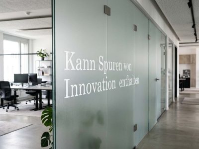 Mehrere schwarze Schriftzüge aus einer maßgeschneiderten Wandfolie als Orientierung über den Kleiderschränken und Kleiderstangen.